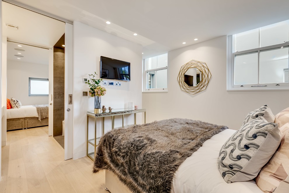 Design ideas for a contemporary bedroom in London with white walls, light hardwood flooring and beige floors.