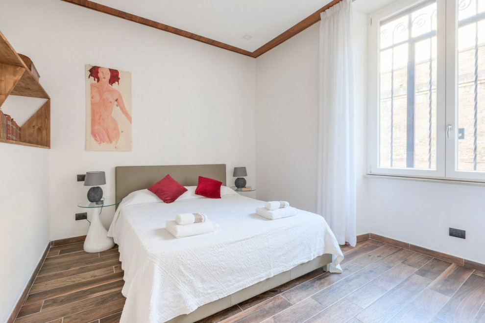 На фото: хозяйская спальня среднего размера в современном стиле с белыми стенами, полом из керамогранита и коричневым полом с