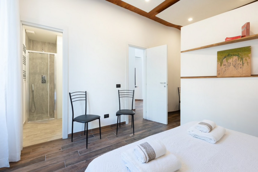 Mittelgroßes Modernes Hauptschlafzimmer mit weißer Wandfarbe, Porzellan-Bodenfliesen und braunem Boden in Rom