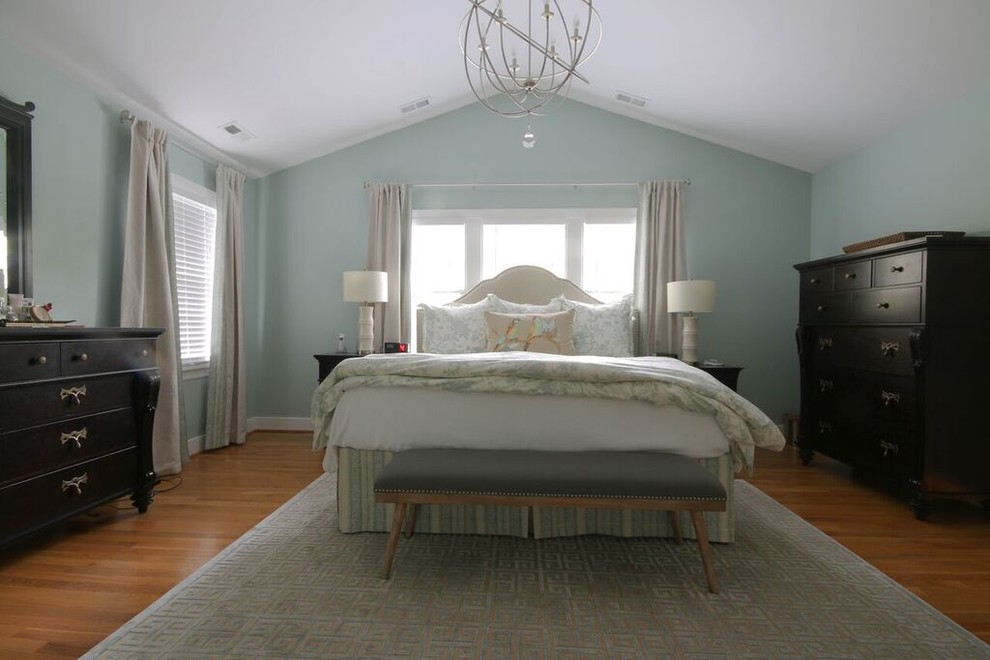 Cette image montre une grande chambre parentale traditionnelle avec un mur bleu, parquet clair et aucune cheminée.