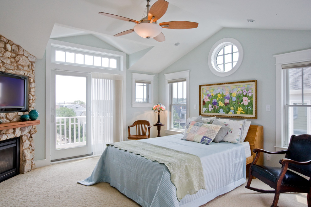 This is an example of a medium sized beach style master and grey and cream bedroom in Other with grey walls, carpet, a corner fireplace, a stone fireplace surround and beige floors.