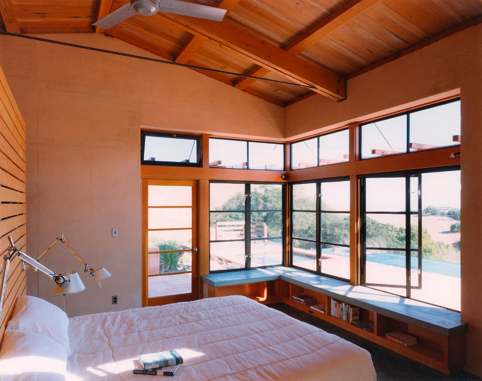 Cette photo montre une petite chambre parentale moderne avec un mur beige et sol en béton ciré.