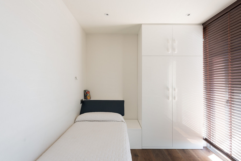 Réalisation d'une petite chambre d'amis design avec un mur blanc, un sol en bois brun et aucune cheminée.