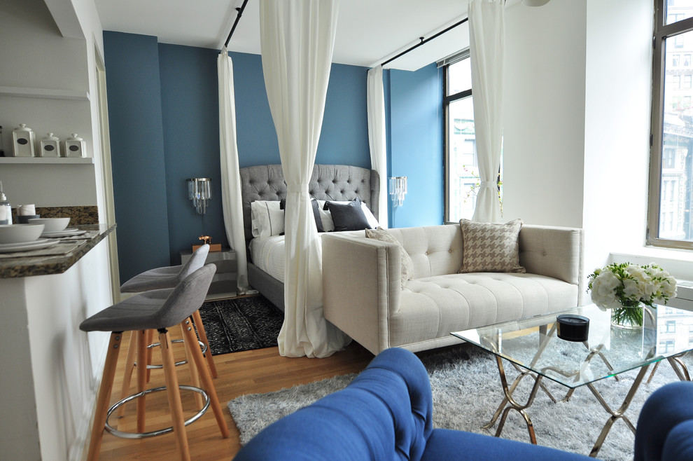 Modelo de dormitorio principal minimalista pequeño con paredes azules y suelo de madera en tonos medios
