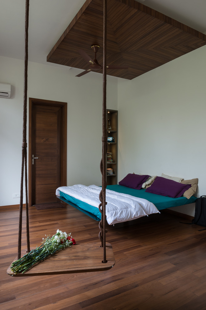 Mittelgroßes Modernes Schlafzimmer mit beiger Wandfarbe und braunem Holzboden in Delhi