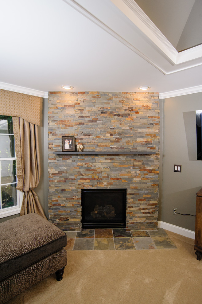 Foto de dormitorio clásico renovado con paredes grises, chimenea de esquina y marco de chimenea de piedra