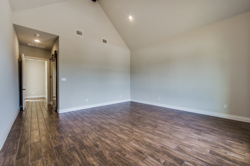 Mittelgroßes Landhausstil Hauptschlafzimmer ohne Kamin mit grauer Wandfarbe, Porzellan-Bodenfliesen und braunem Boden in Austin
