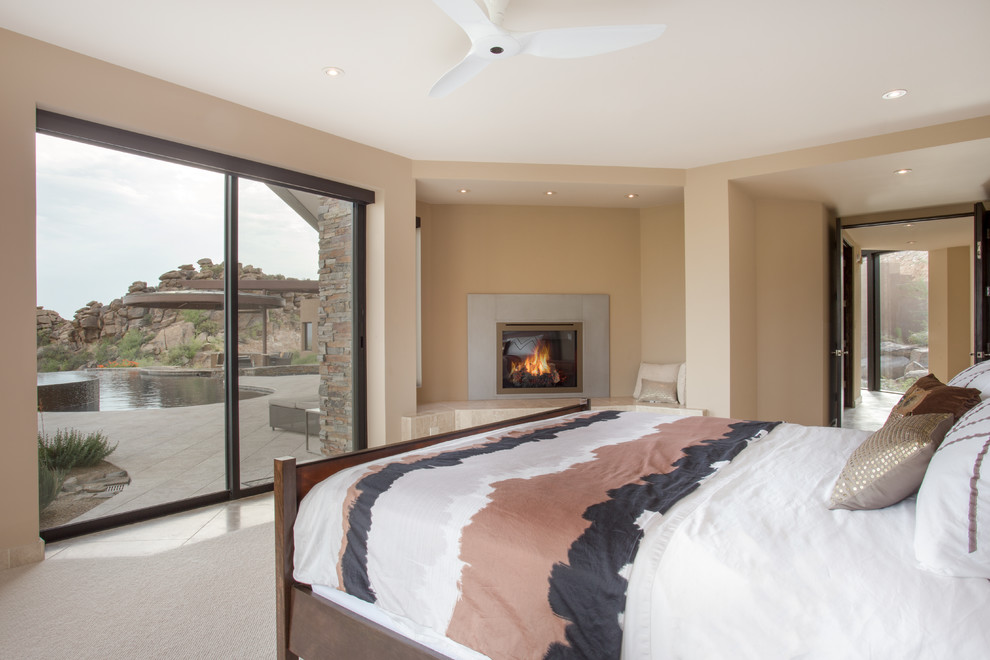 フェニックスにある広いコンテンポラリースタイルのおしゃれな主寝室 (ベージュの壁、ライムストーンの床、コーナー設置型暖炉、石材の暖炉まわり)