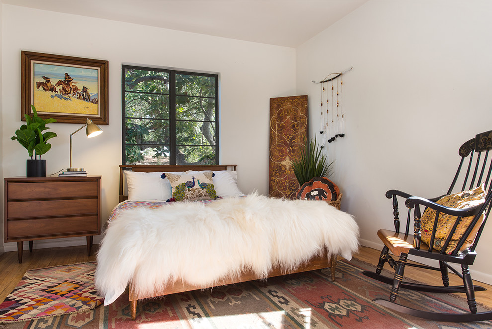 Idée de décoration pour une chambre d'amis bohème avec un mur blanc, un sol en bois brun et un sol beige.