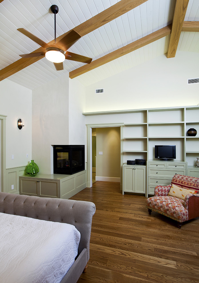 Medium sized contemporary master bedroom in Los Angeles with white walls, medium hardwood flooring, a corner fireplace, a metal fireplace surround and brown floors.