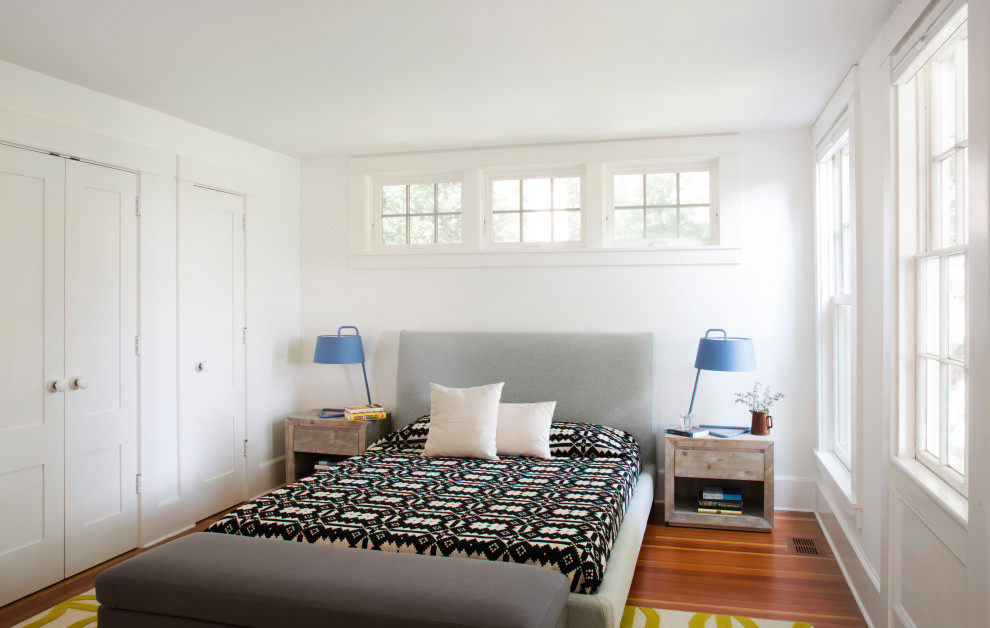 This is an example of a coastal bedroom in Boston with white walls, medium hardwood flooring and brown floors.