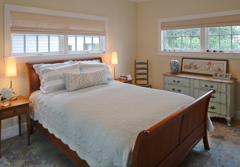 Modelo de habitación de invitados costera de tamaño medio sin chimenea con suelo de madera clara y paredes beige