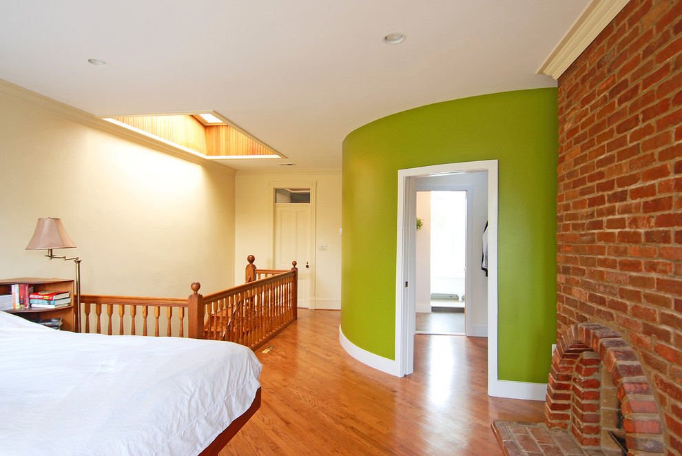 Idee per una grande camera da letto stile loft boho chic con pareti verdi, pavimento in legno massello medio, cornice del camino in mattoni, camino classico e pavimento marrone