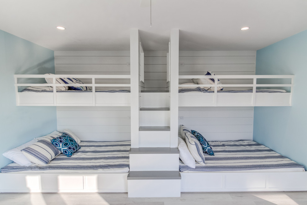 Ejemplo de habitación de invitados costera de tamaño medio con paredes azules, suelo vinílico y suelo gris