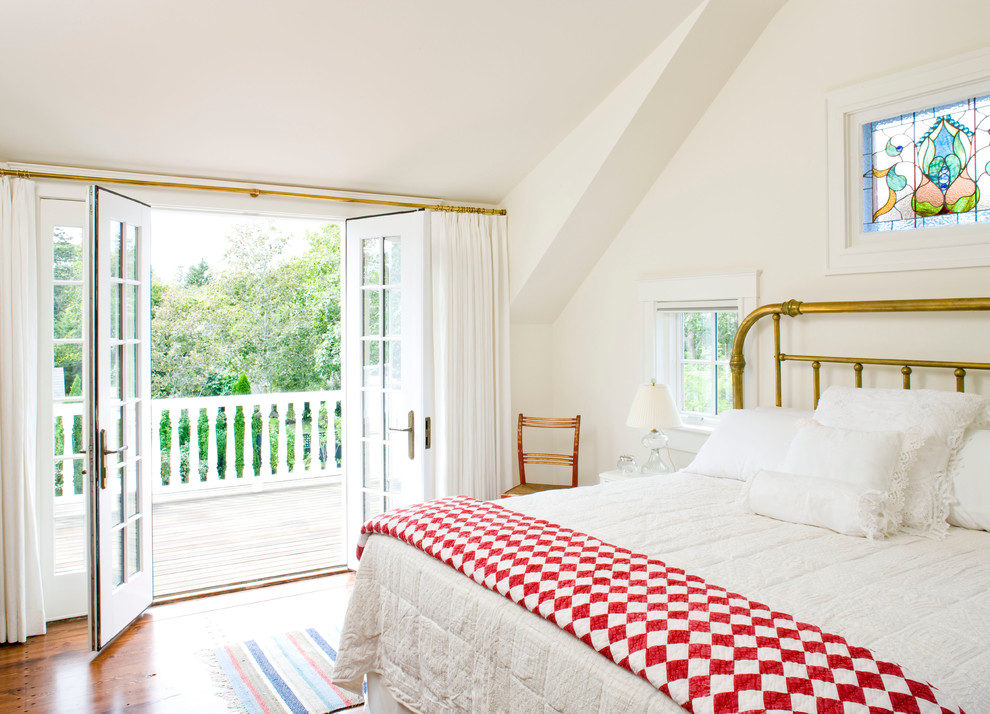 Modelo de dormitorio tradicional grande con paredes blancas y suelo de madera en tonos medios