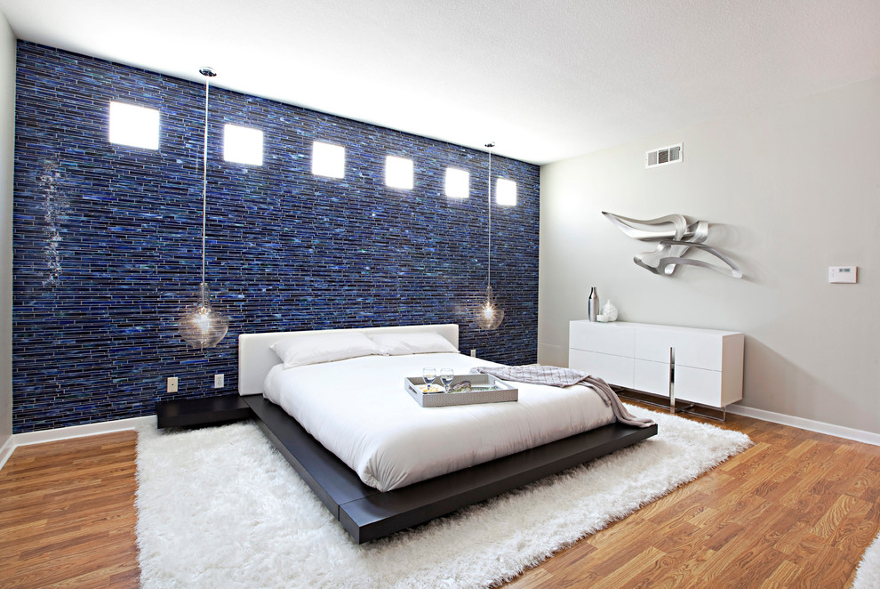 Großes Modernes Hauptschlafzimmer mit beiger Wandfarbe, braunem Holzboden, Kamin und verputzter Kaminumrandung in Orange County