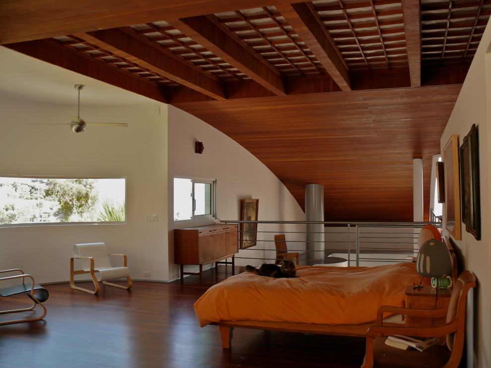 Cette image montre une chambre mansardée ou avec mezzanine design avec un mur blanc, parquet foncé et un sol marron.