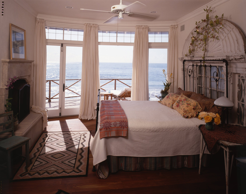 Modelo de dormitorio marinero con paredes beige, suelo de madera en tonos medios y todas las chimeneas