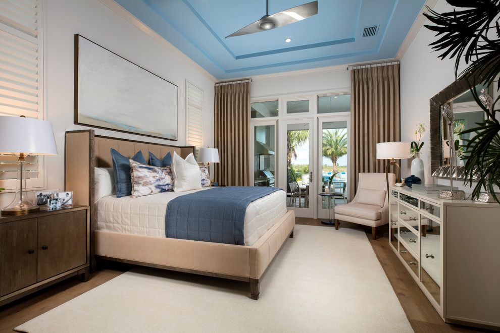 Nautical master bedroom in Miami with white walls, medium hardwood flooring and no fireplace.