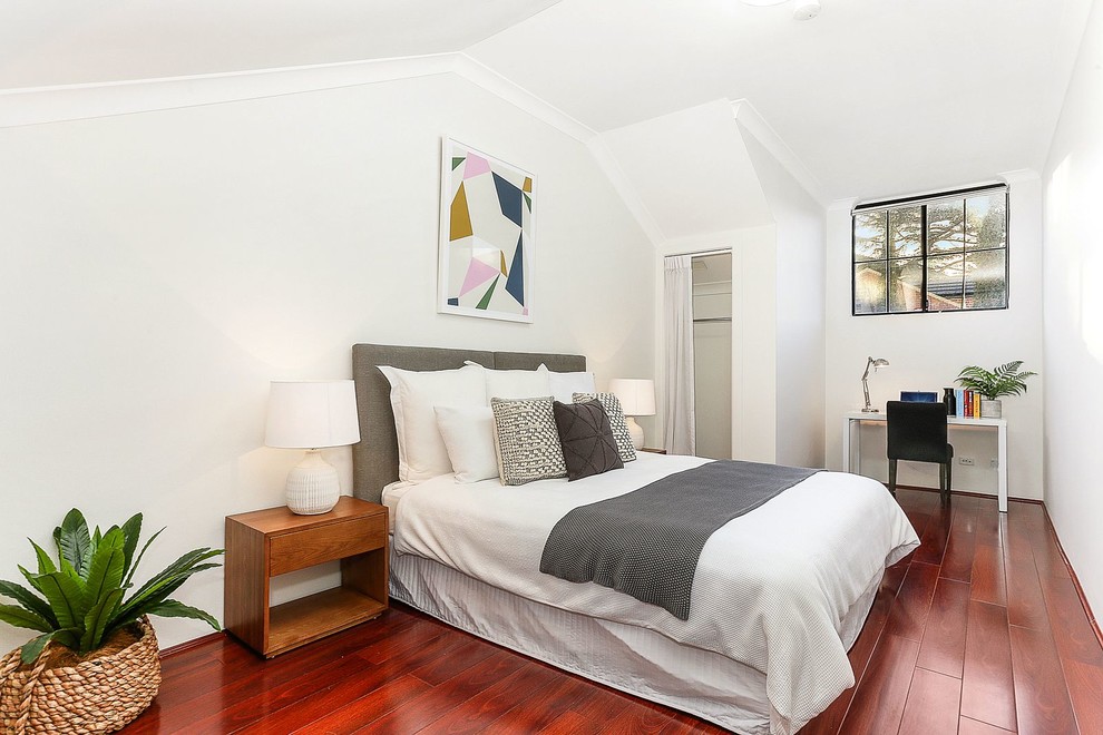 Foto de dormitorio actual con paredes blancas, suelo de madera en tonos medios y suelo rojo