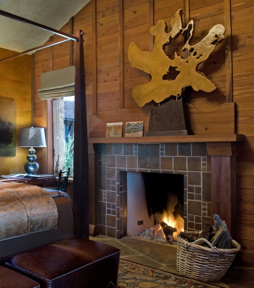 На фото: спальня среднего размера в стиле рустика с коричневыми стенами, полом из сланца, стандартным камином и фасадом камина из плитки с