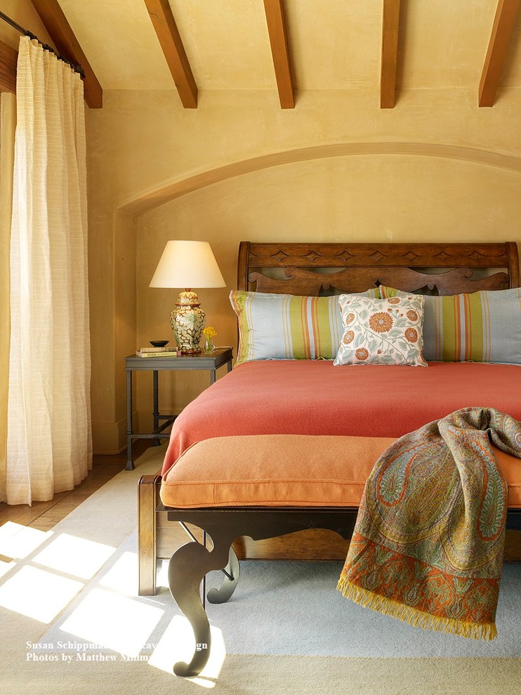 Modelo de habitación de invitados mediterránea grande con paredes amarillas y suelo de madera en tonos medios