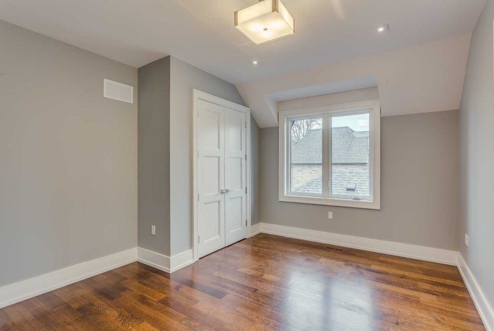 Cette image montre une chambre parentale minimaliste de taille moyenne avec un mur gris, un sol en bois brun, une cheminée d'angle et un manteau de cheminée en pierre.