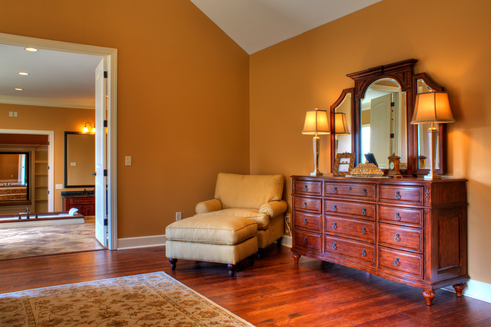 Immagine di una grande camera matrimoniale classica con pareti marroni e pavimento in legno massello medio