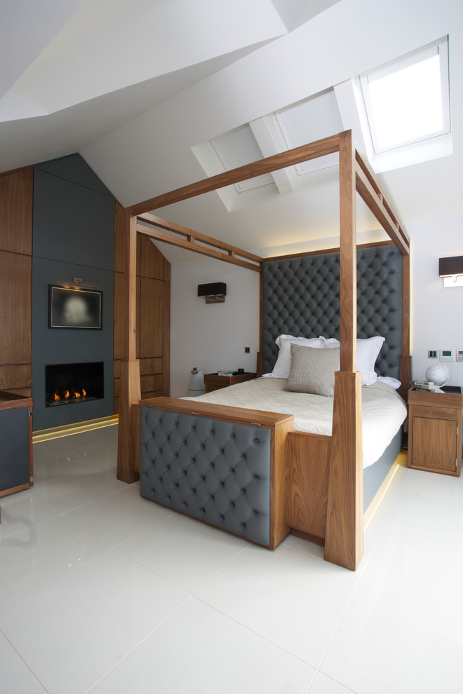 Large trendy master bedroom photo in London with white walls and a standard fireplace