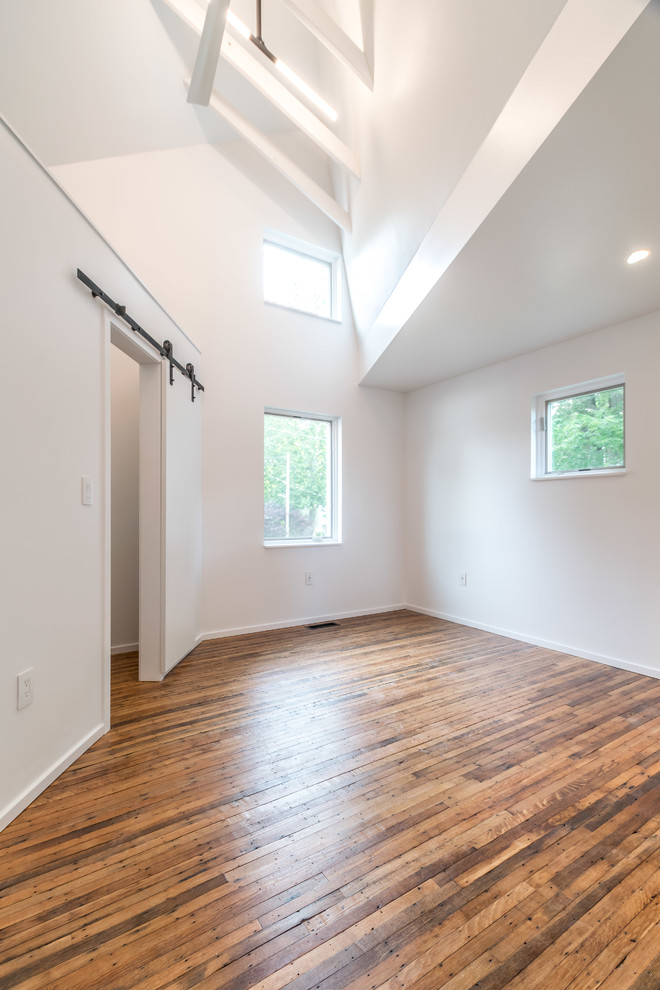 Exemple d'une petite chambre tendance avec un mur blanc, un sol en bois brun, aucune cheminée et un sol marron.
