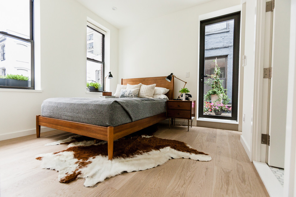 Nordisk inredning av ett sovrum, med vita väggar, ljust trägolv och beiget golv
