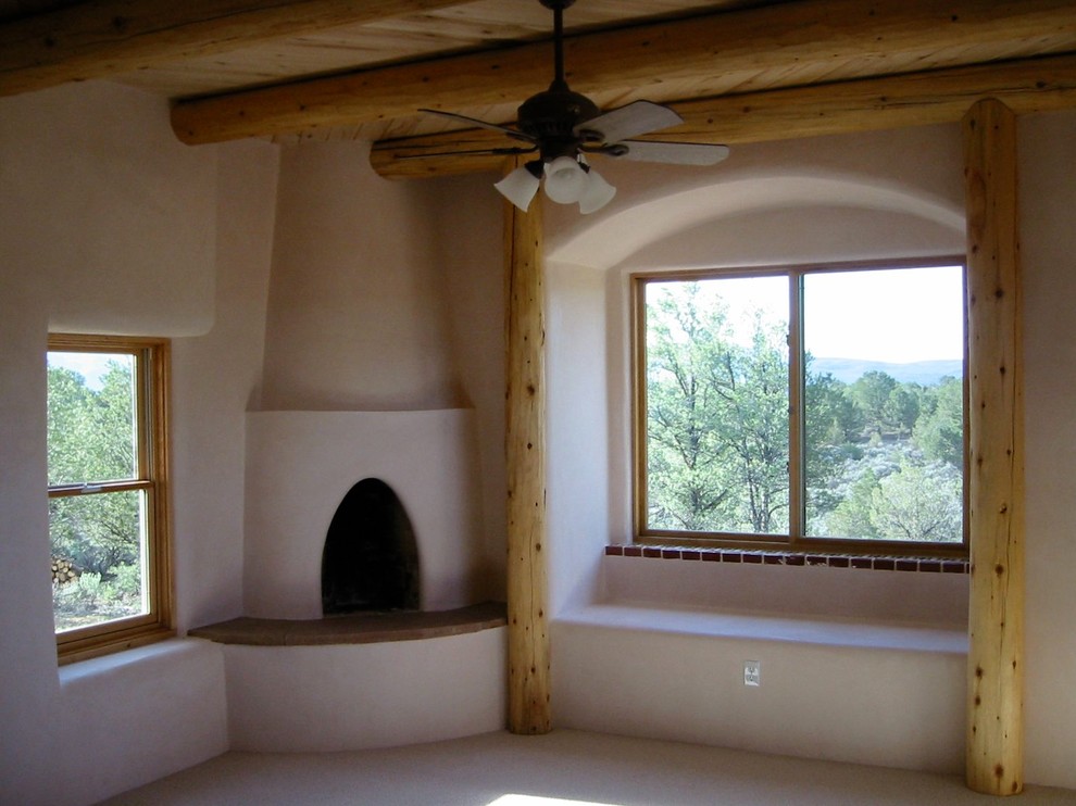 Inspiration pour une chambre bohème de taille moyenne avec un mur beige, une cheminée d'angle et un manteau de cheminée en plâtre.