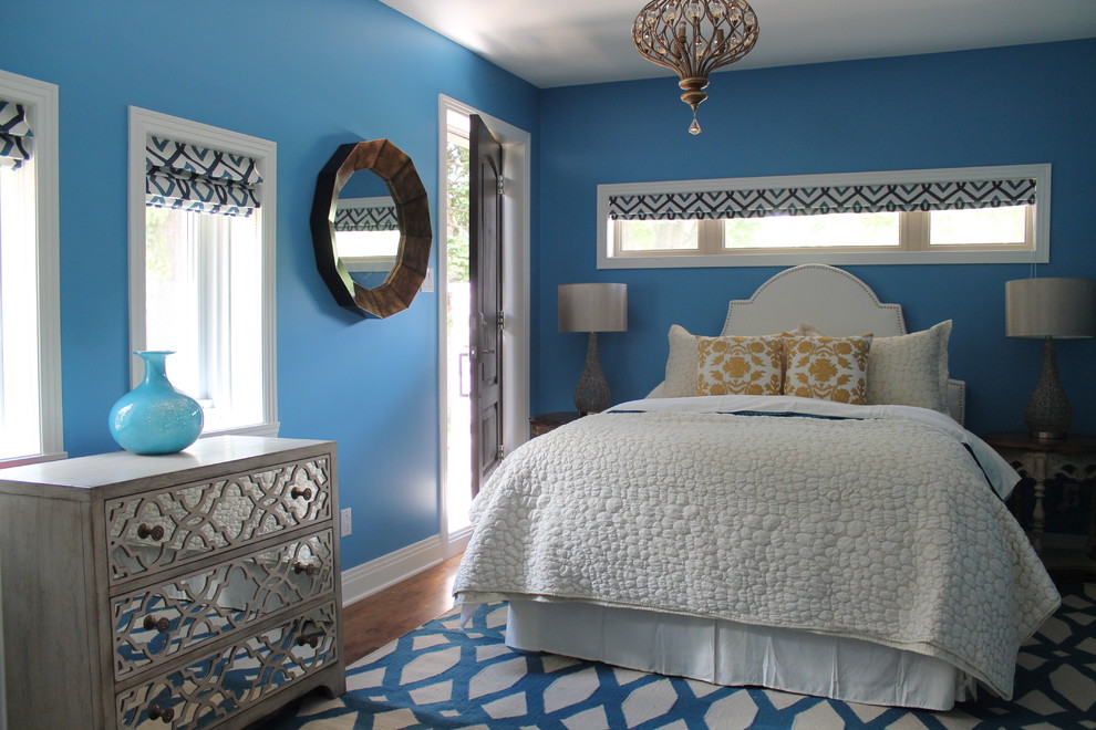 Modelo de habitación de invitados mediterránea de tamaño medio con paredes azules y suelo de madera en tonos medios