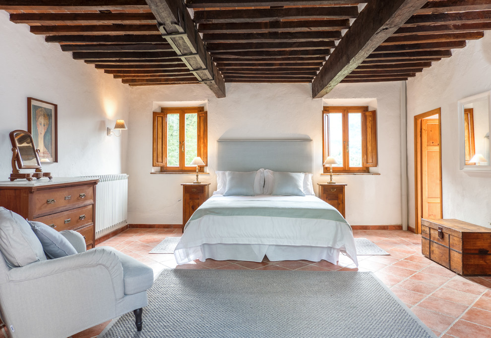 Esempio di una camera matrimoniale mediterranea di medie dimensioni con pareti bianche, pavimento in terracotta e pavimento arancione
