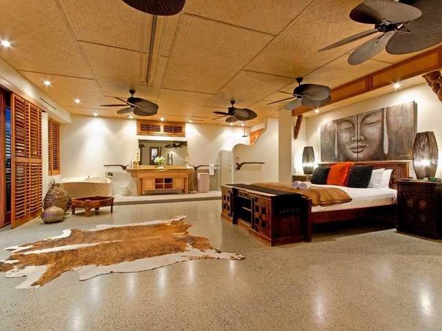 Ejemplo de dormitorio principal exótico extra grande con paredes blancas y suelo de cemento