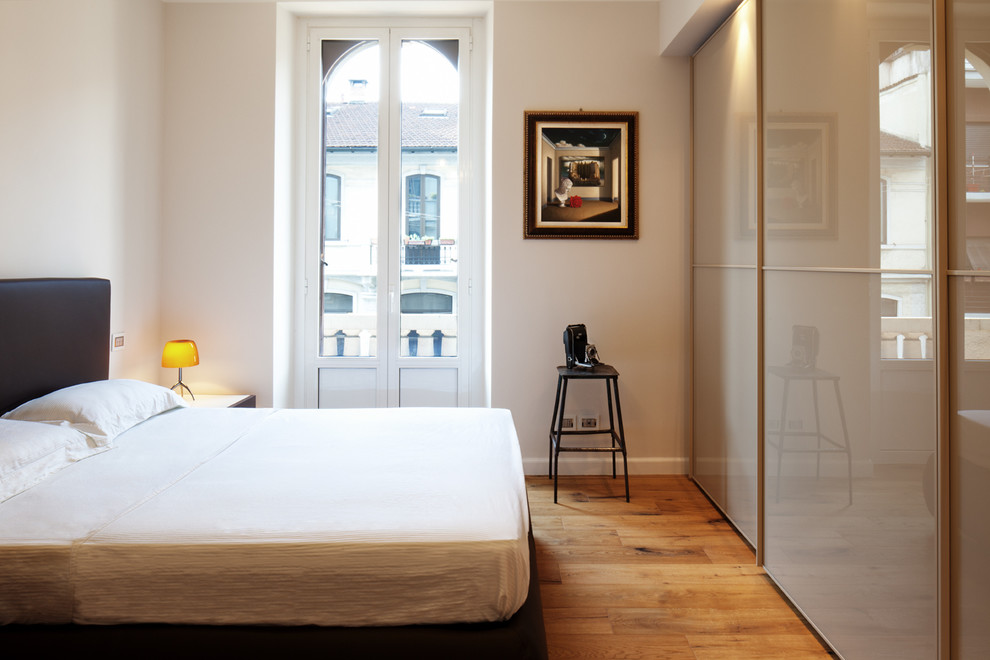 Foto de dormitorio principal actual con paredes blancas y suelo de madera en tonos medios