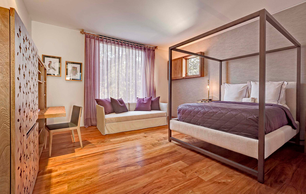 Cette photo montre une chambre tendance avec un mur gris et un sol en bois brun.
