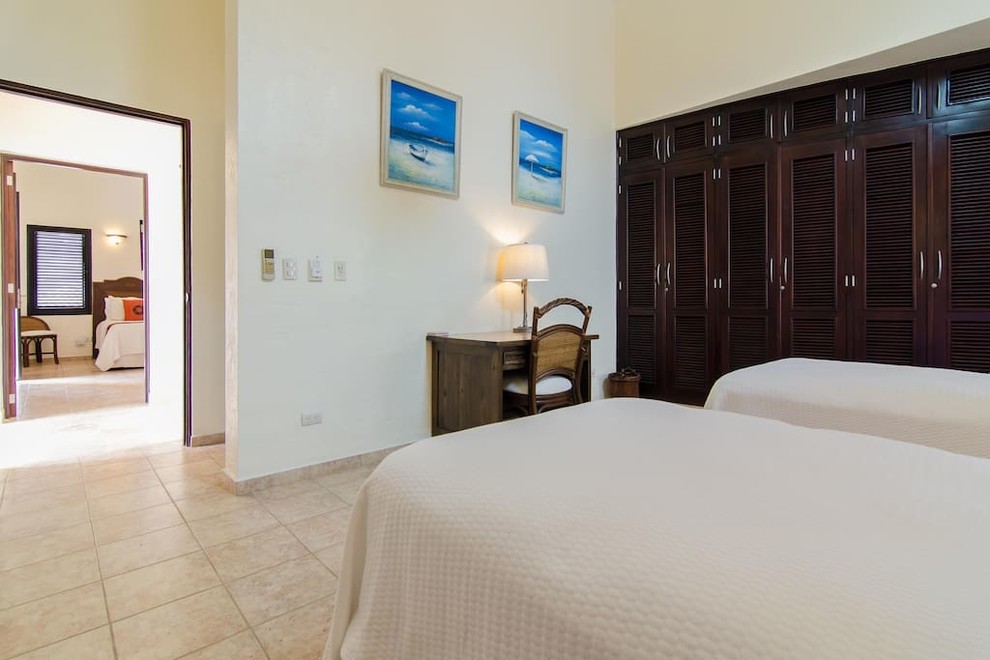 Diseño de habitación de invitados tropical grande con paredes blancas, suelo de travertino y suelo beige