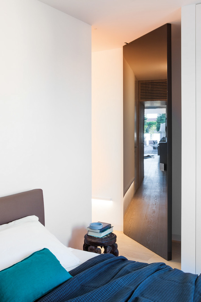 Imagen de habitación de invitados actual pequeña con paredes blancas y suelo de madera clara