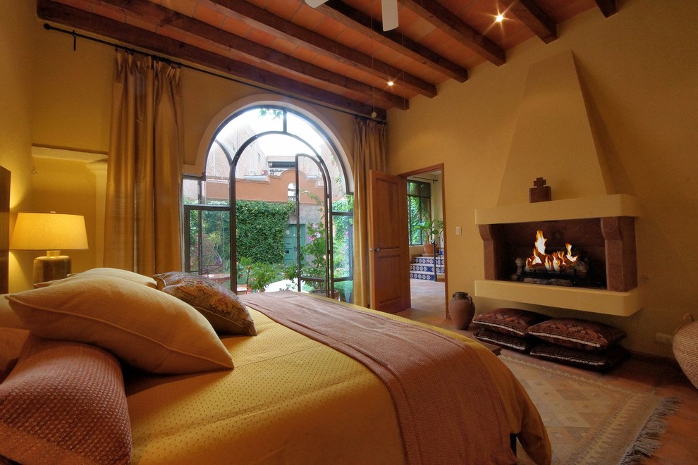 ミネアポリスにある中くらいな地中海スタイルのおしゃれな主寝室 (黄色い壁、テラコッタタイルの床、標準型暖炉、石材の暖炉まわり) のレイアウト