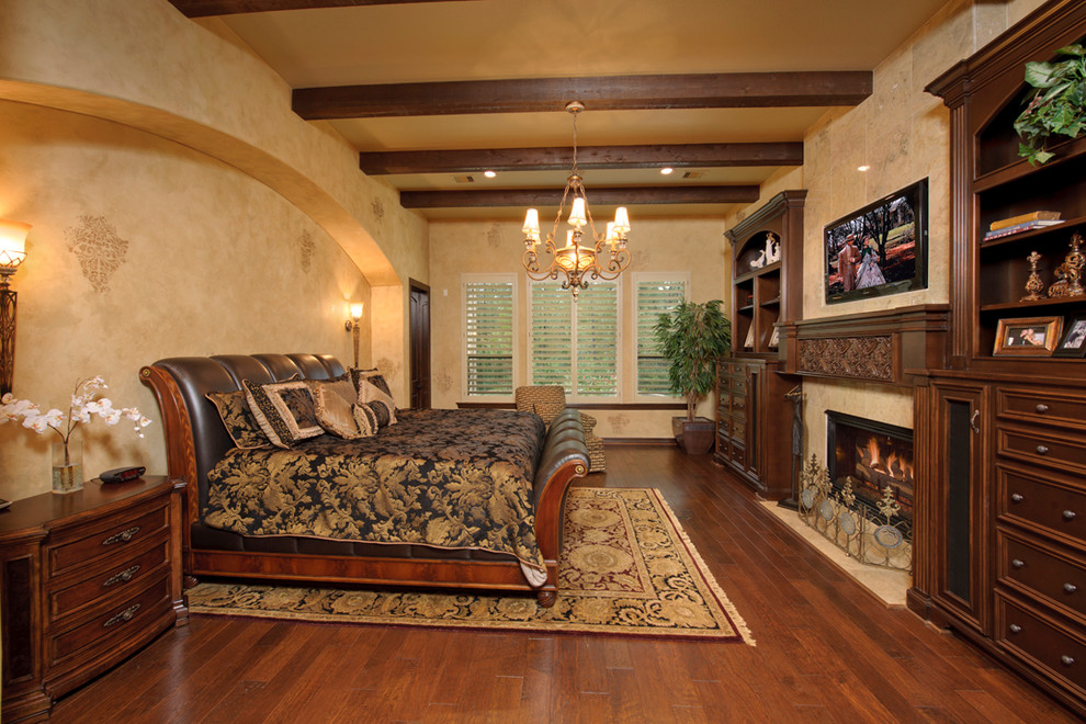 This is an example of a mediterranean bedroom in Houston with beige walls, medium hardwood flooring and a standard fireplace.