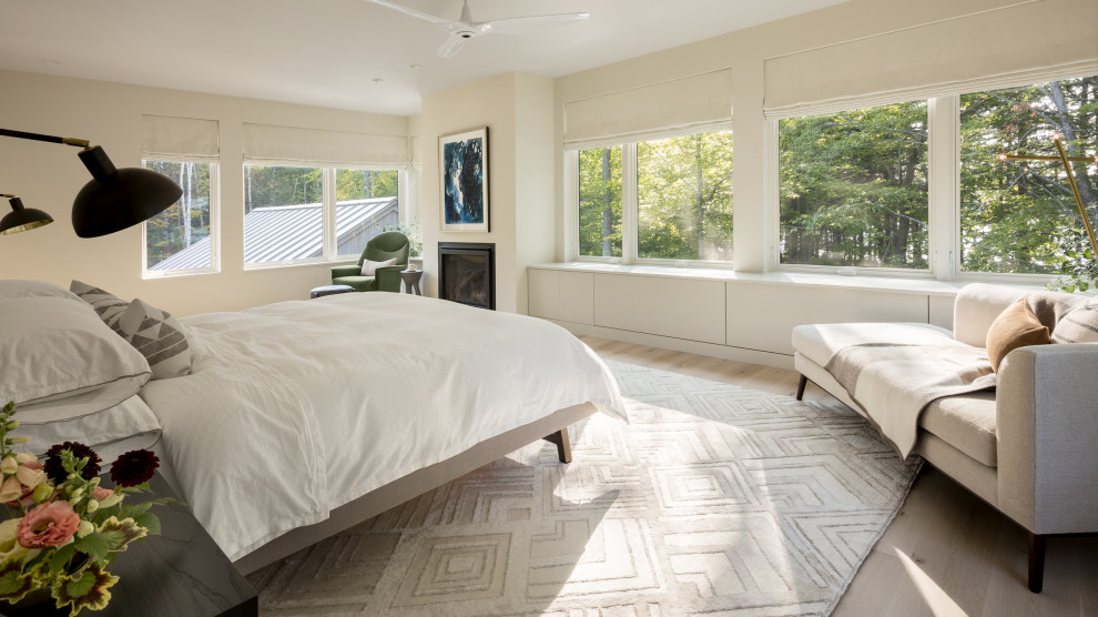 Esempio di una camera da letto costiera con pareti bianche, pavimento in legno massello medio, camino classico e pavimento marrone