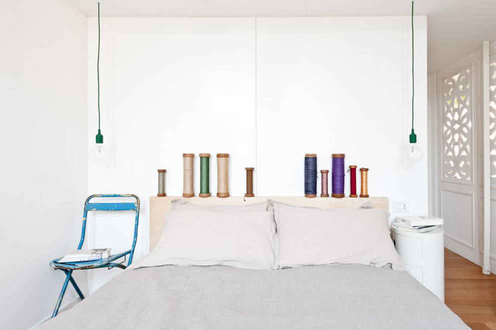Modelo de dormitorio ecléctico con paredes blancas y suelo de madera clara