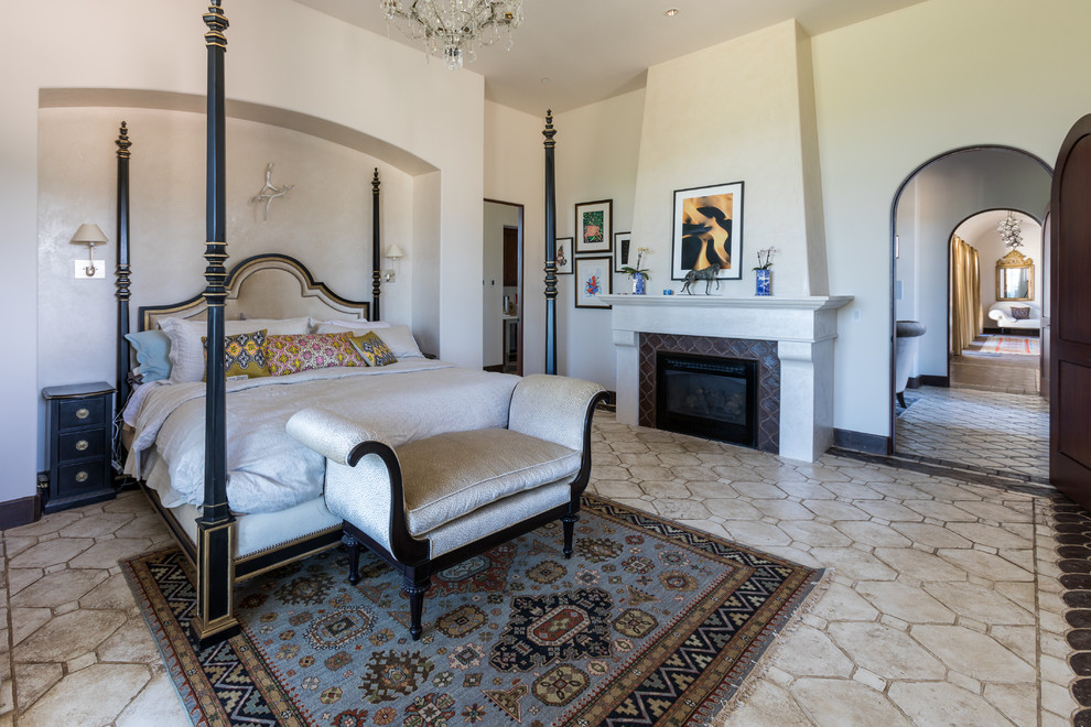 Exemple d'une chambre parentale méditerranéenne avec un mur beige, une cheminée standard, un manteau de cheminée en carrelage et un sol beige.