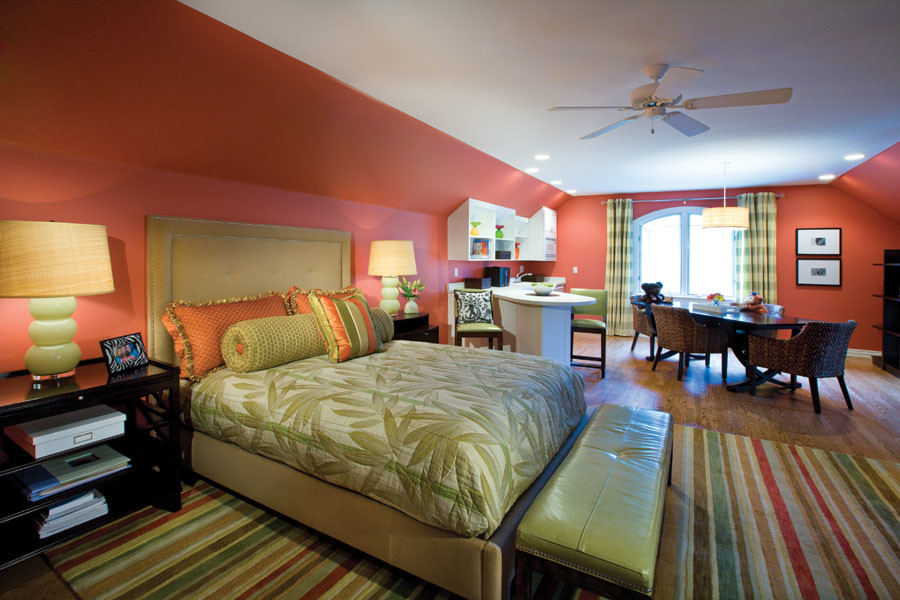 На фото: большая гостевая спальня (комната для гостей) в стиле фьюжн с оранжевыми стенами, паркетным полом среднего тона и коричневым полом без камина с