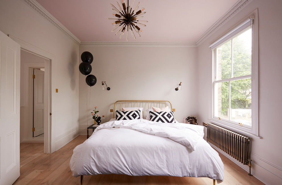 Mittelgroßes Skandinavisches Schlafzimmer mit rosa Wandfarbe, braunem Holzboden und braunem Boden in London