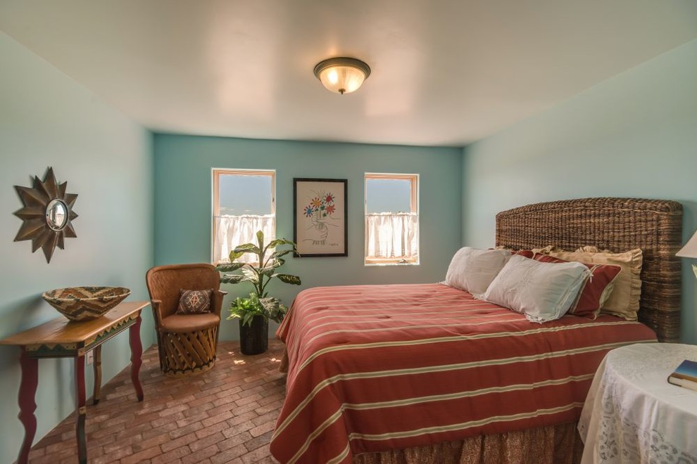 Modelo de habitación de invitados de estilo americano de tamaño medio sin chimenea con paredes azules, suelo de ladrillo y suelo rojo