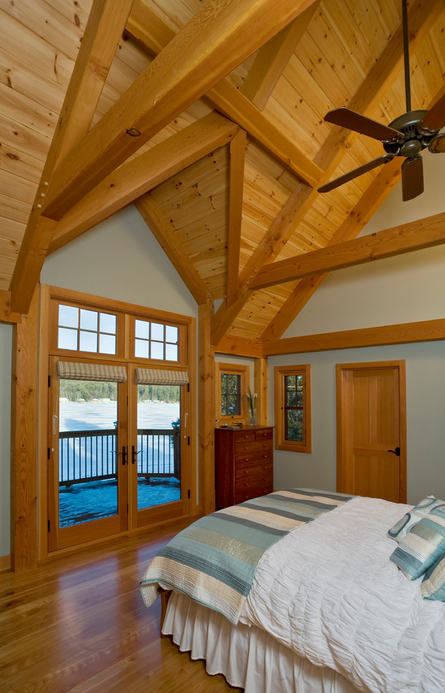 Cette image montre une grande chambre parentale chalet avec un sol en bois brun et un mur bleu.