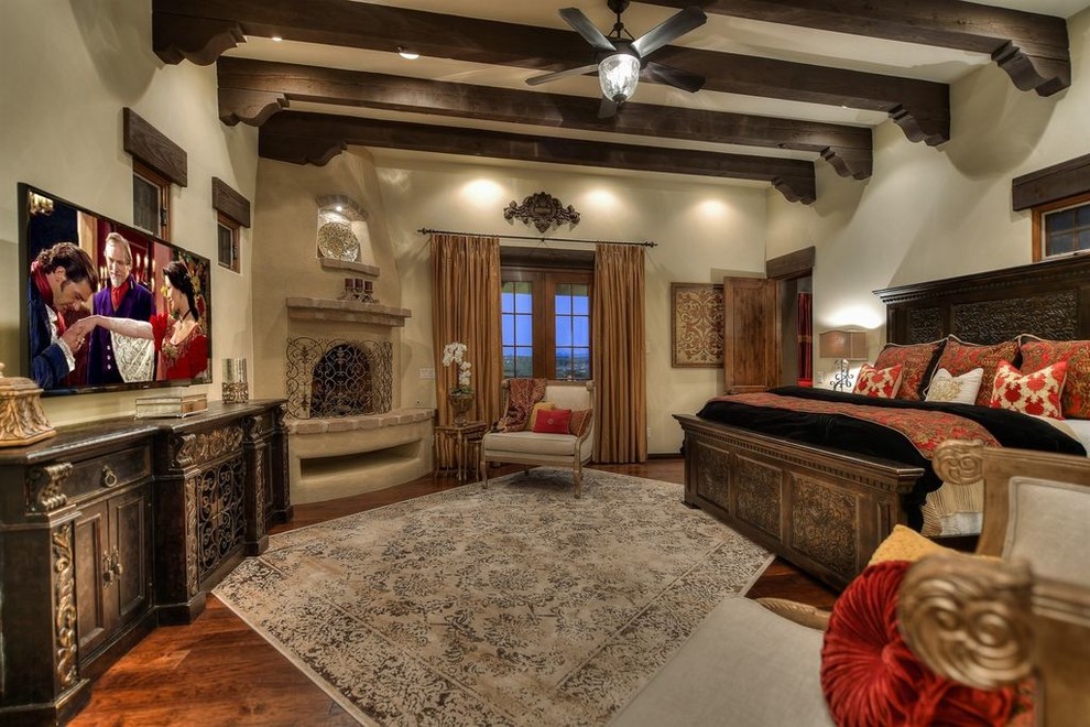 Geräumiges Mediterranes Hauptschlafzimmer mit beiger Wandfarbe, dunklem Holzboden, Eckkamin und Kaminumrandung aus Beton in Phoenix