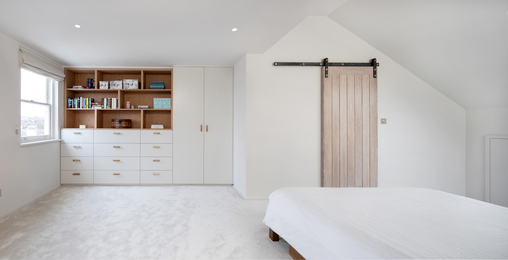 Medium sized traditional guest bedroom in London with white walls, carpet and beige floors.